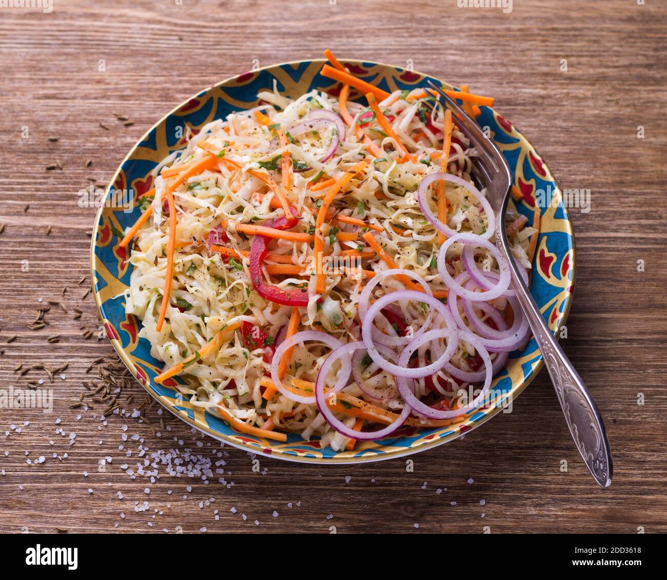 Insalata di cavolo con carote, pepe rosso, cipolle, coriandolo e spezie in un piatto luminoso su un tavolo di legno, fuoco selettivo. Cibo sano e delizioso Foto Stock