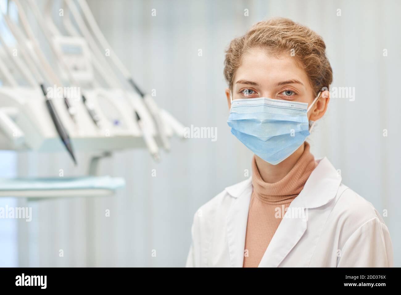 Ritratto di giovane dentista femminile in maschera protettiva guardando macchina fotografica in piedi presso la clinica odontoiatrica Foto Stock