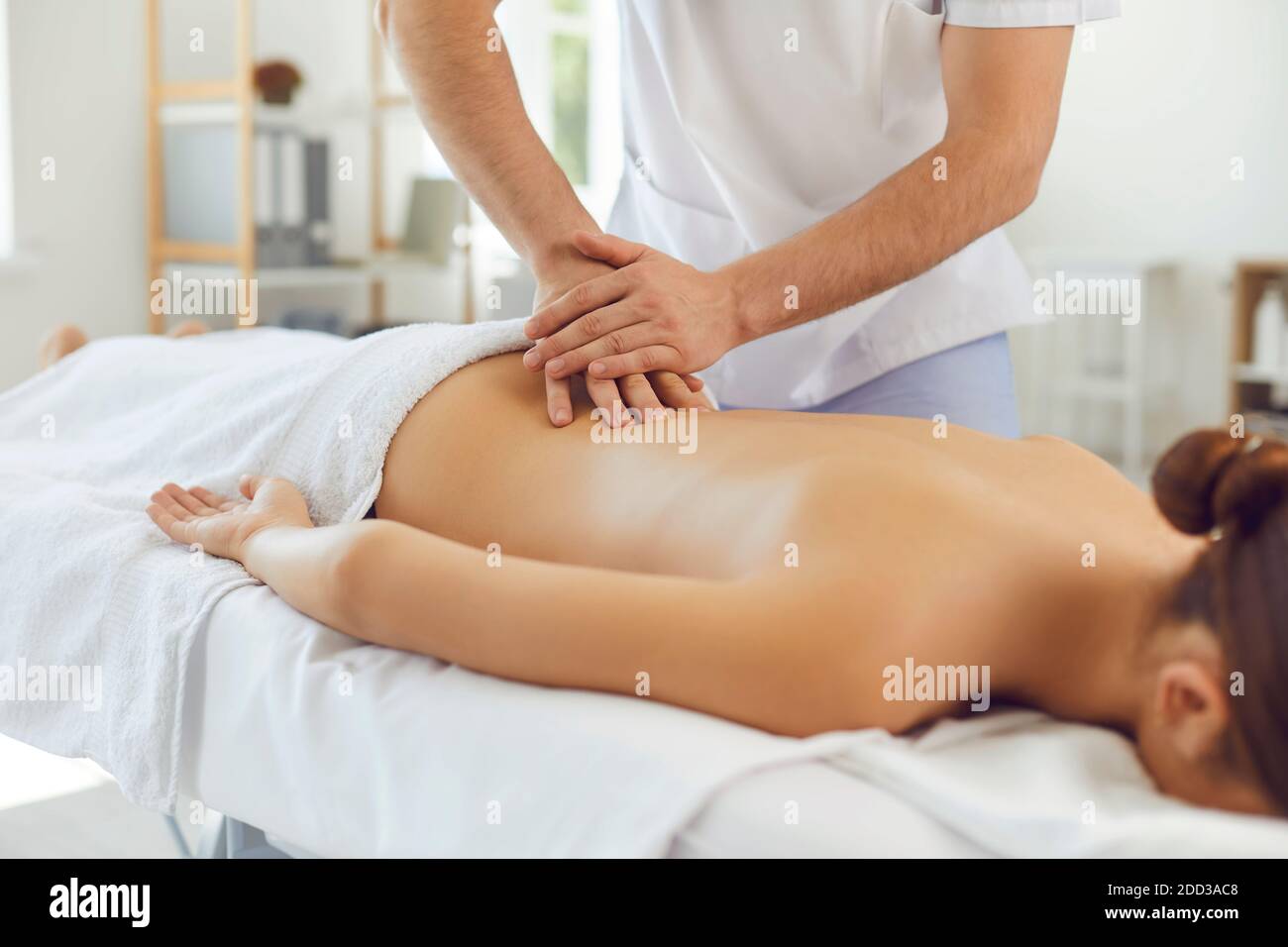 Massaggiatore professionista che fa massaggio alla schiena per la giovane donna che si sdraiava tavolo da massaggio nel centro benessere Foto Stock