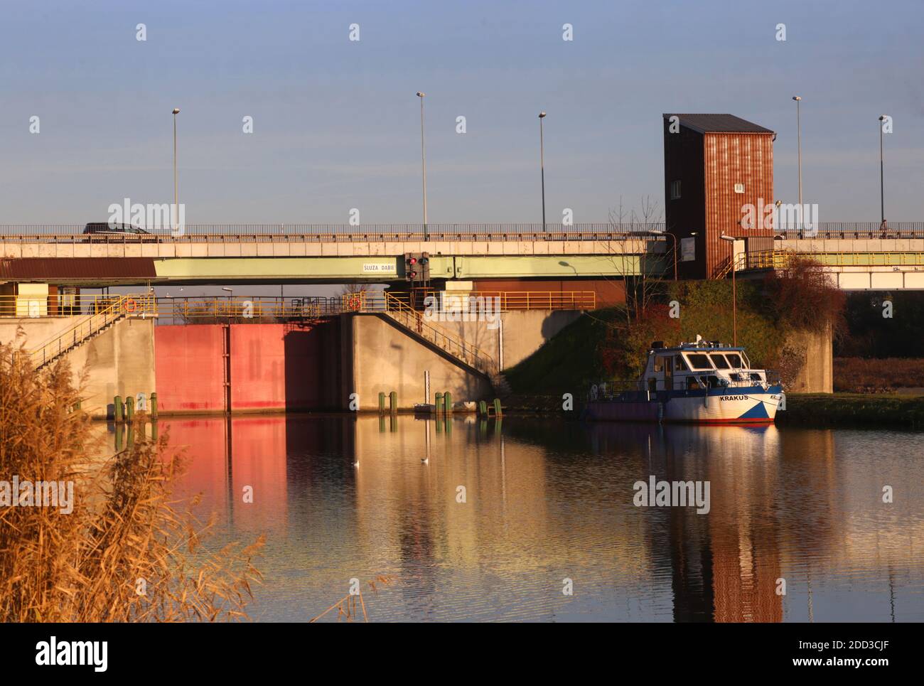 Cracovia. Cracovia. Polonia. Una diga sul fiume Vistola con il cancello rosso di waterlock e piccola nave ormeggiata. Foto Stock