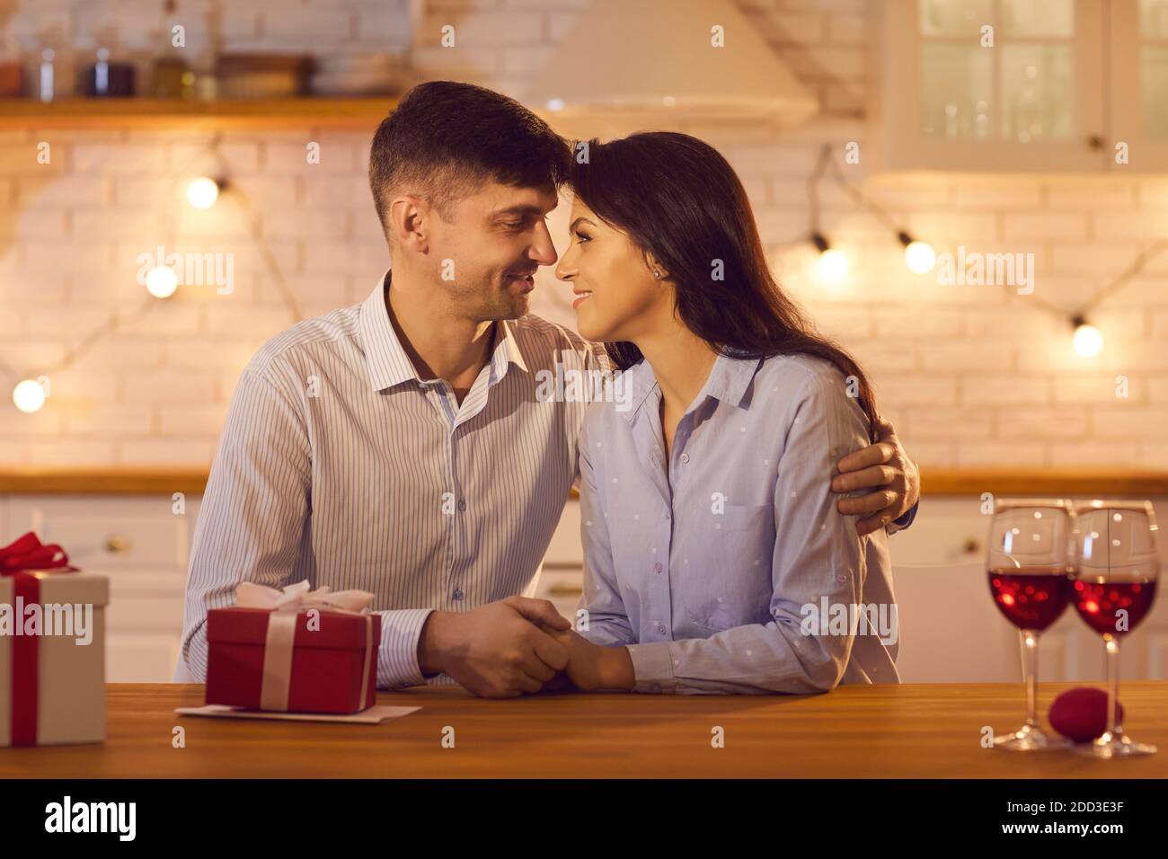 Uomo e donna che tengono le mani teneramente e amorevolmente guardando gli occhi felici l'uno dell'altro. Foto Stock