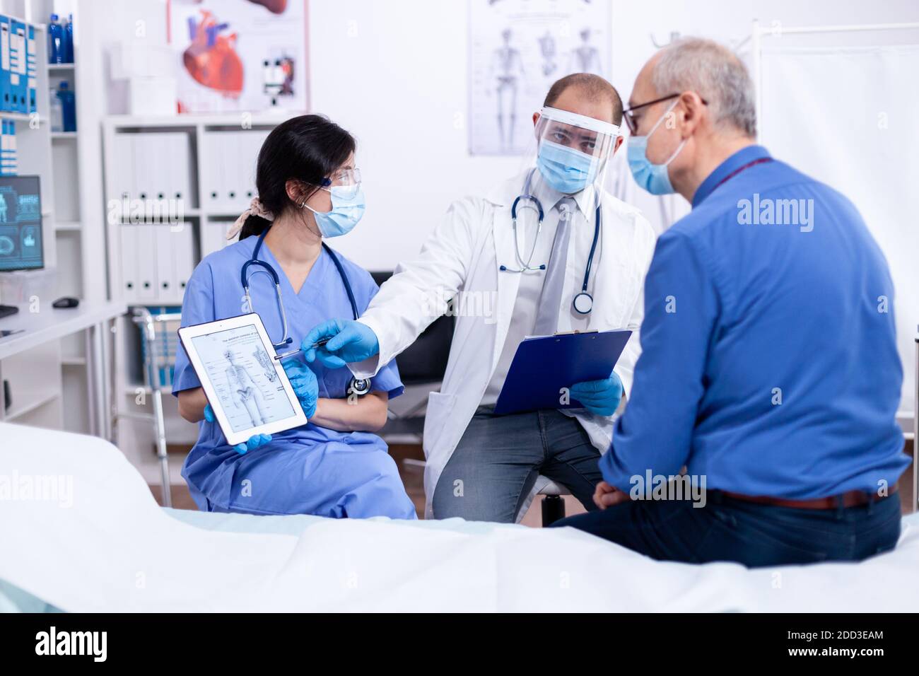 Paziente che guarda la radiografia del suo scheletro durante la consultazione con il medico in ospedale indossare la protezione contro covid-19. Visita medica per infezioni, malattie e diagnosi. Foto Stock