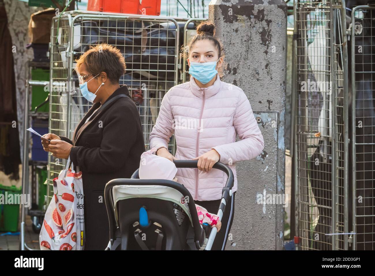 Londra, UK - 3 novembre 2020 - una giovane madre che indossa una maschera mentre spinge un passeggino nel mercato di Walthamstow Foto Stock
