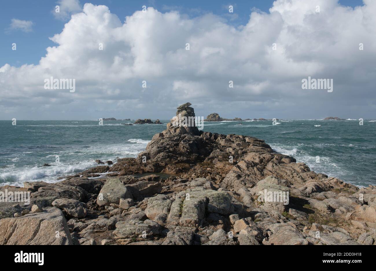 Massi di granito sulla costa con un cielo blu nuvoloso e il mare ruvido sfondo sull'isola di Bryher nelle isole di Scilly, Inghilterra, Regno Unito Foto Stock