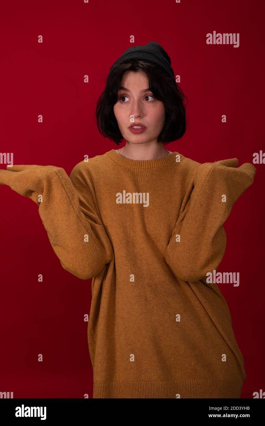 hipster ragazza in nero maglia cappuccio e maglione in posa con mani a maniche lunghe Foto Stock