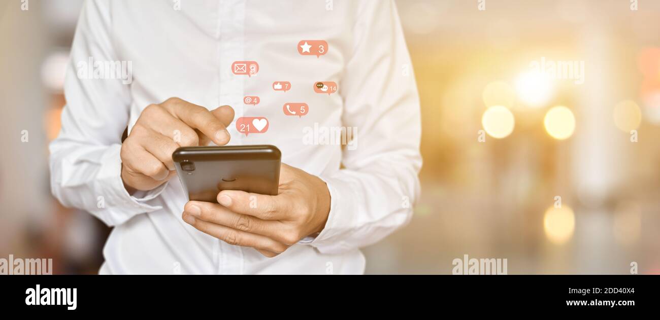 Primo piano di un uomo che utilizza lo smartphone mobile con icone social e multimediali. Concetto di tecnologia di marketing o aziendale. Foto Stock