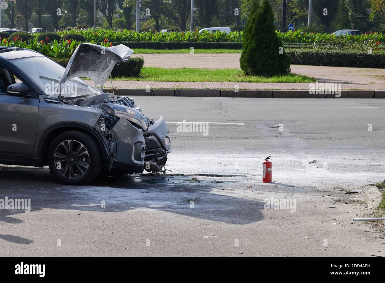 Auto argentata dopo un incidente con cofano aperto. Veicolo dopo un incendio con impatto frontale. Estintore vicino alla vettura. Foto di concetto di velocità. Foto Stock