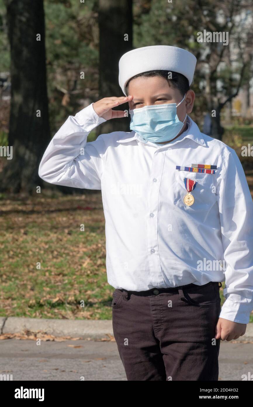 Un ragazzo adolescente nel corpo Navale dei Cadetti degli Stati Uniti si trova all'attenzione e saluta vicino all'Unisfero nel Flushing Meadows Corona Park a Queens, New York City. Foto Stock