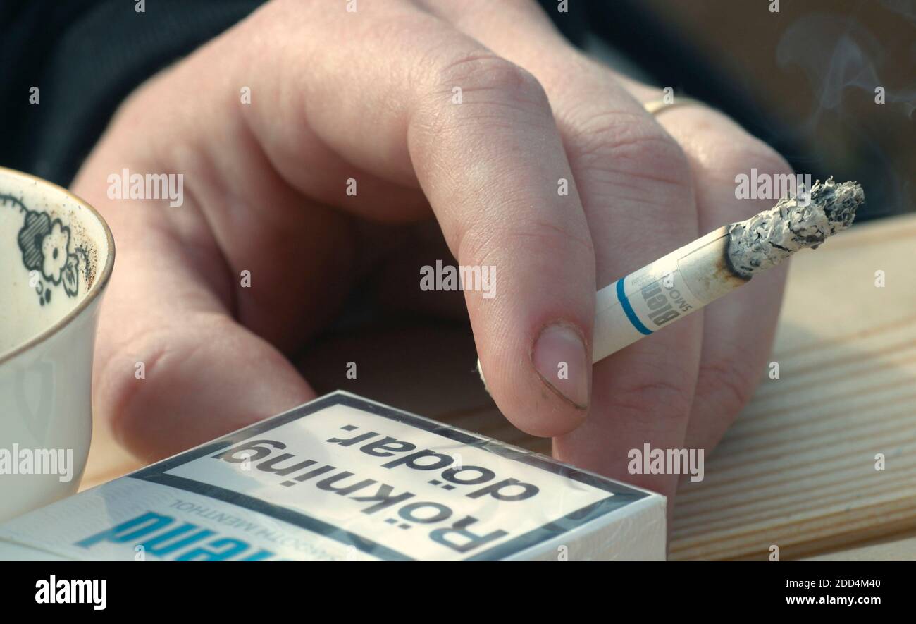 Primo piano di Donna che tiene in mano la sigaretta bruciante accanto a. confezione di sigarette di miscelazione Foto Stock
