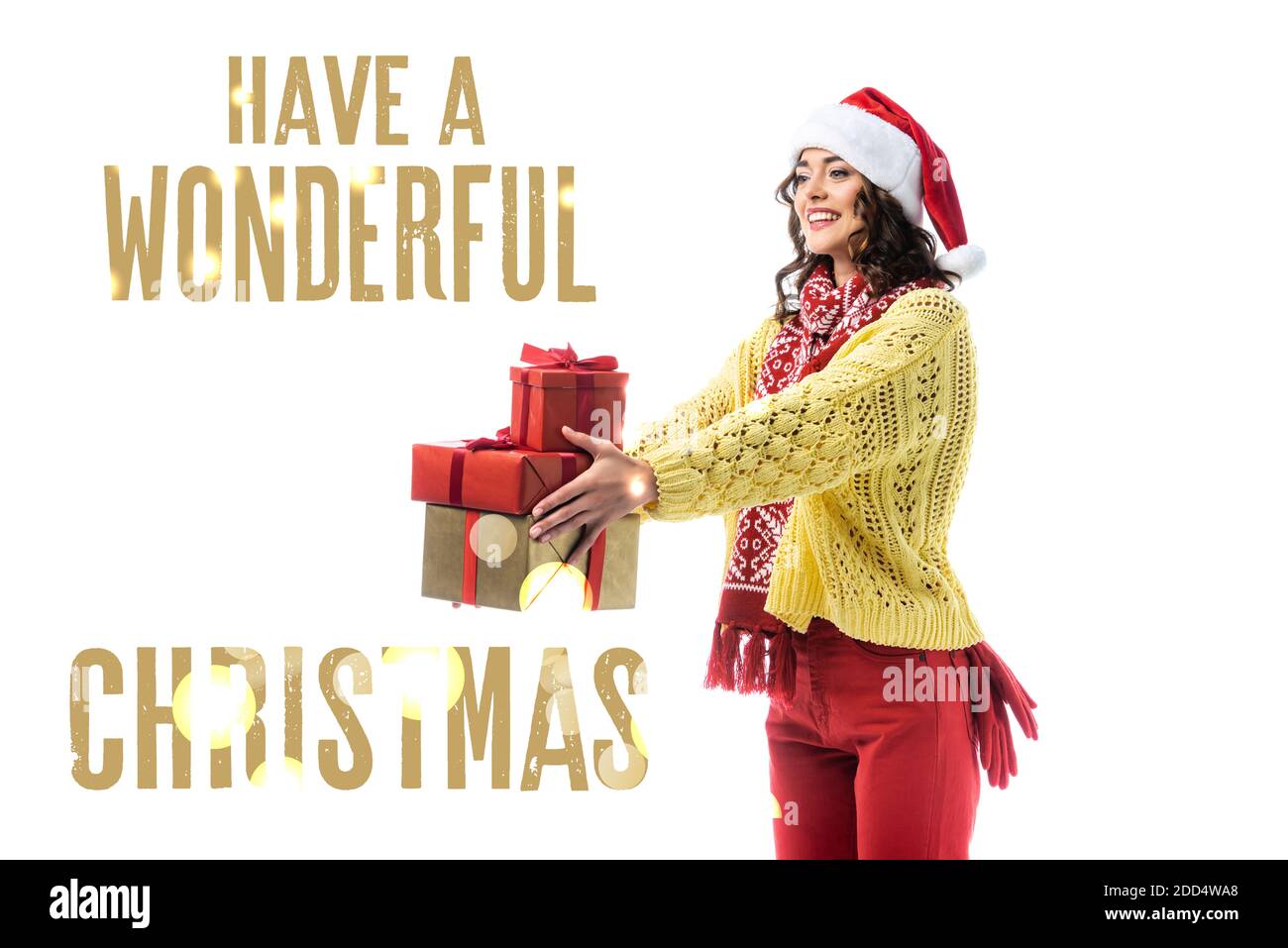 gioiosa giovane donna nel cappello di santa, sciarpa e maglione a maglia che tiene i regali vicino hanno una meravigliosa scritta di natale su bianco Foto Stock