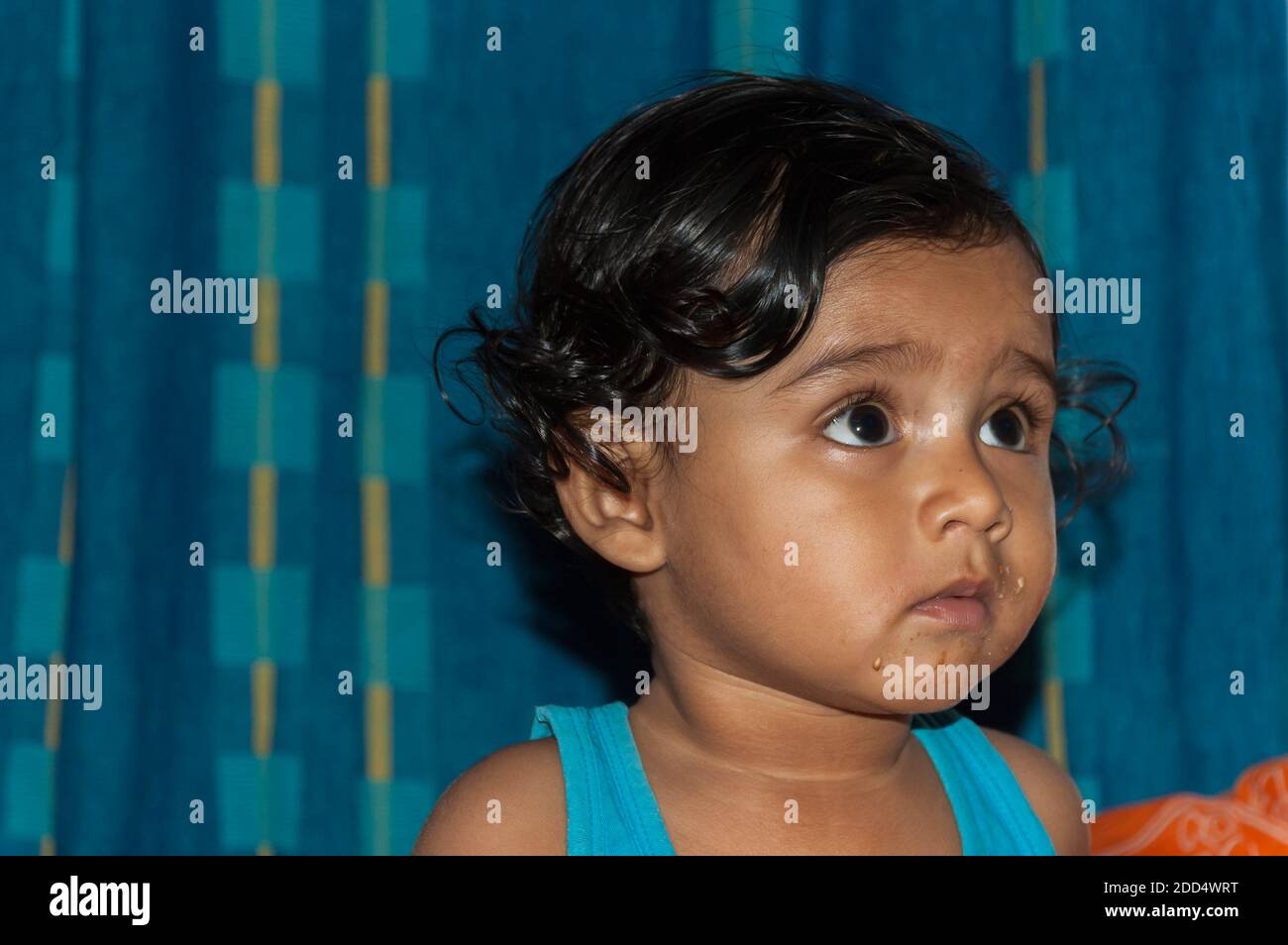 Un bambino indiano asiatico con cibo sul viso. Foto Stock