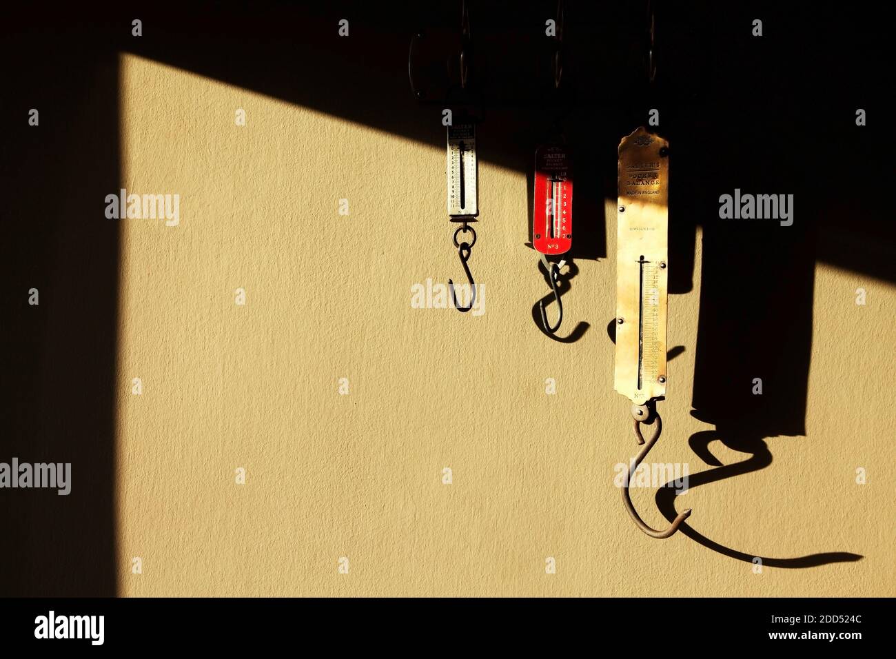 Tre bilance a molla per la misurazione dei pesi degli articoli appesi ai ganci. Foto Stock Tre bilance a molla per la misurazione dei pesi degli articoli appesi ai ganci. Foto Stock