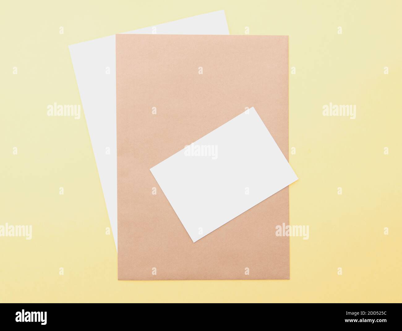 Composizione con fogli bianchi e marroni su sfondo giallo, layout con spazio per il testo, vista dall'alto Foto Stock