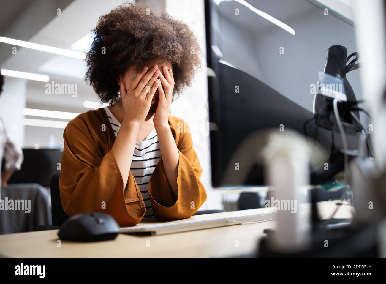 Oberati di lavoro e frustrati giovane donna nella parte anteriore del computer in ufficio Foto Stock