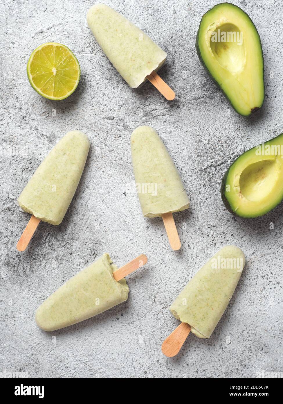 Pop sicle di avocado di tiglio vegano crudi fatte in casa. Gelato verde senza zucchero, non caseario su sfondo grigio. Vista dall'alto. Idee e ricette per spuntini sani, dessert o frullati. Verticale. Foto Stock