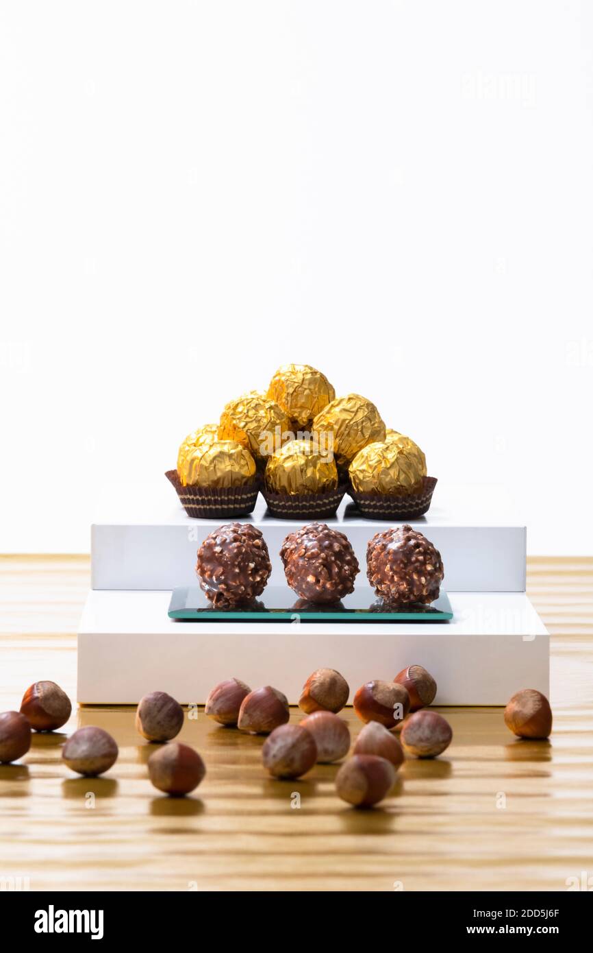 Focalizzazione selettiva di dolci di cioccolato e nocciole splendidamente avvolti e non avvolti con nocciole fuori fuoco. Concetto di pasticceria al cioccolato. Foto Stock