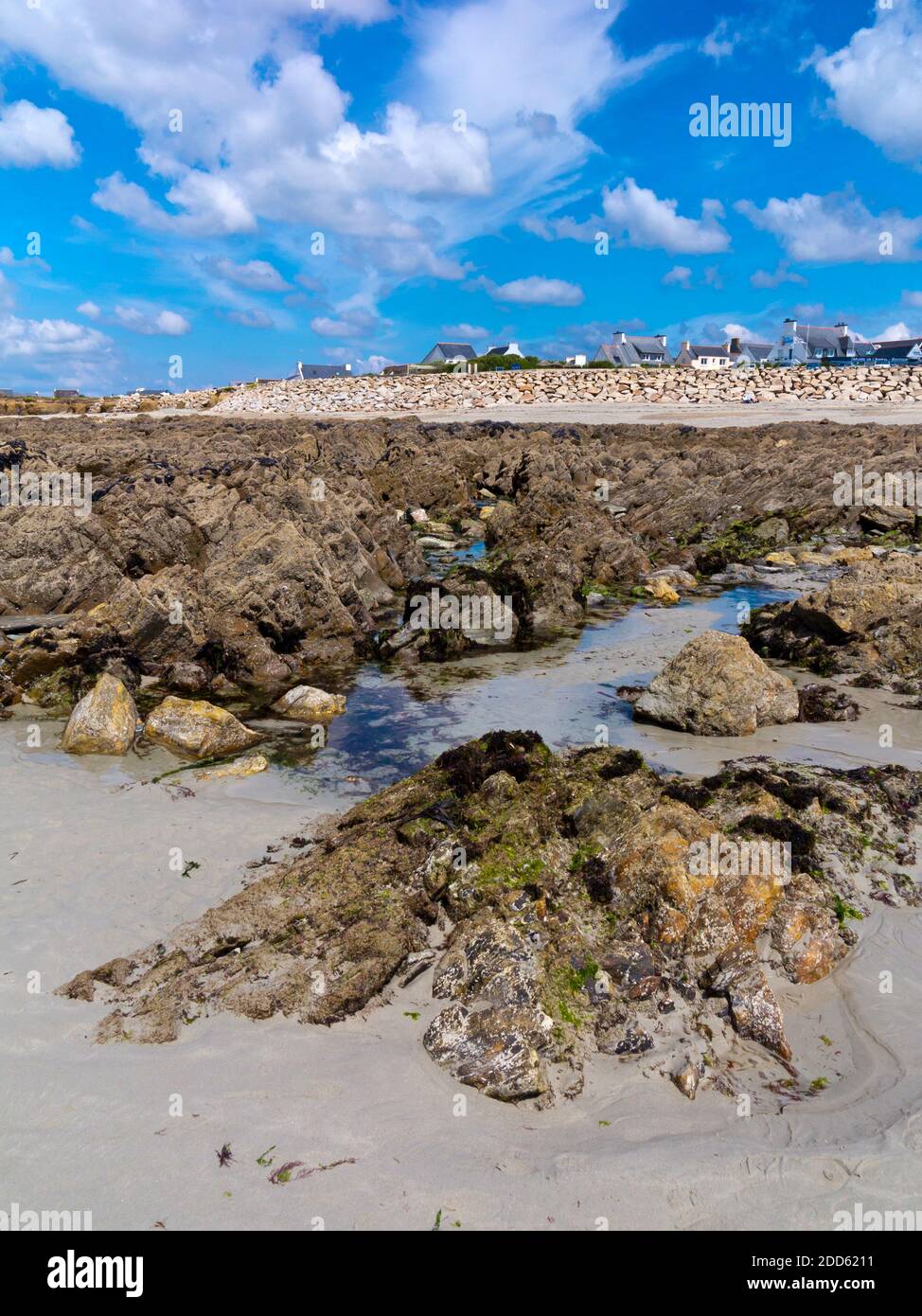 Bassa marea sulla spiaggia di Plage de Penhors, Pouldreuzic, Finistere nel nord-ovest della Bretagna, Francia con case visibili in lontananza. Foto Stock