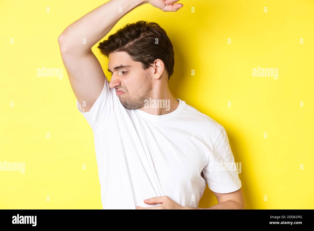 L'uomo nel sudore puzzava la sua ascella, in piedi in una t-shirt bianca e  grimacing da vestiti stinky Foto stock - Alamy