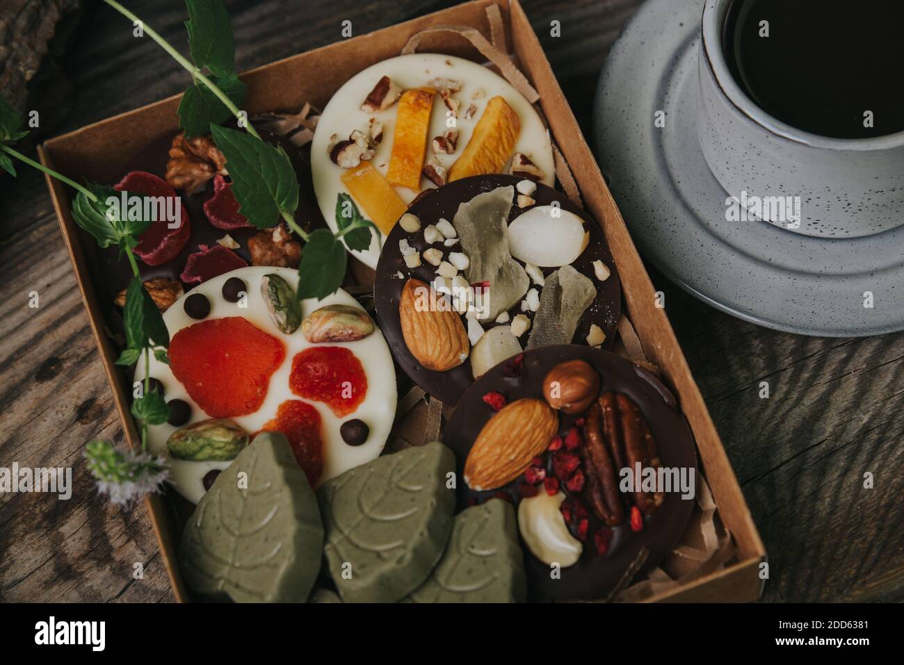 Cioccolatini con frutta secca in una scatola artigianale e una tazza di caffè espresso. Foto Stock Cioccolatini con frutta secca in una scatola artigianale e una tazza di caffè espresso. Foto Stock
