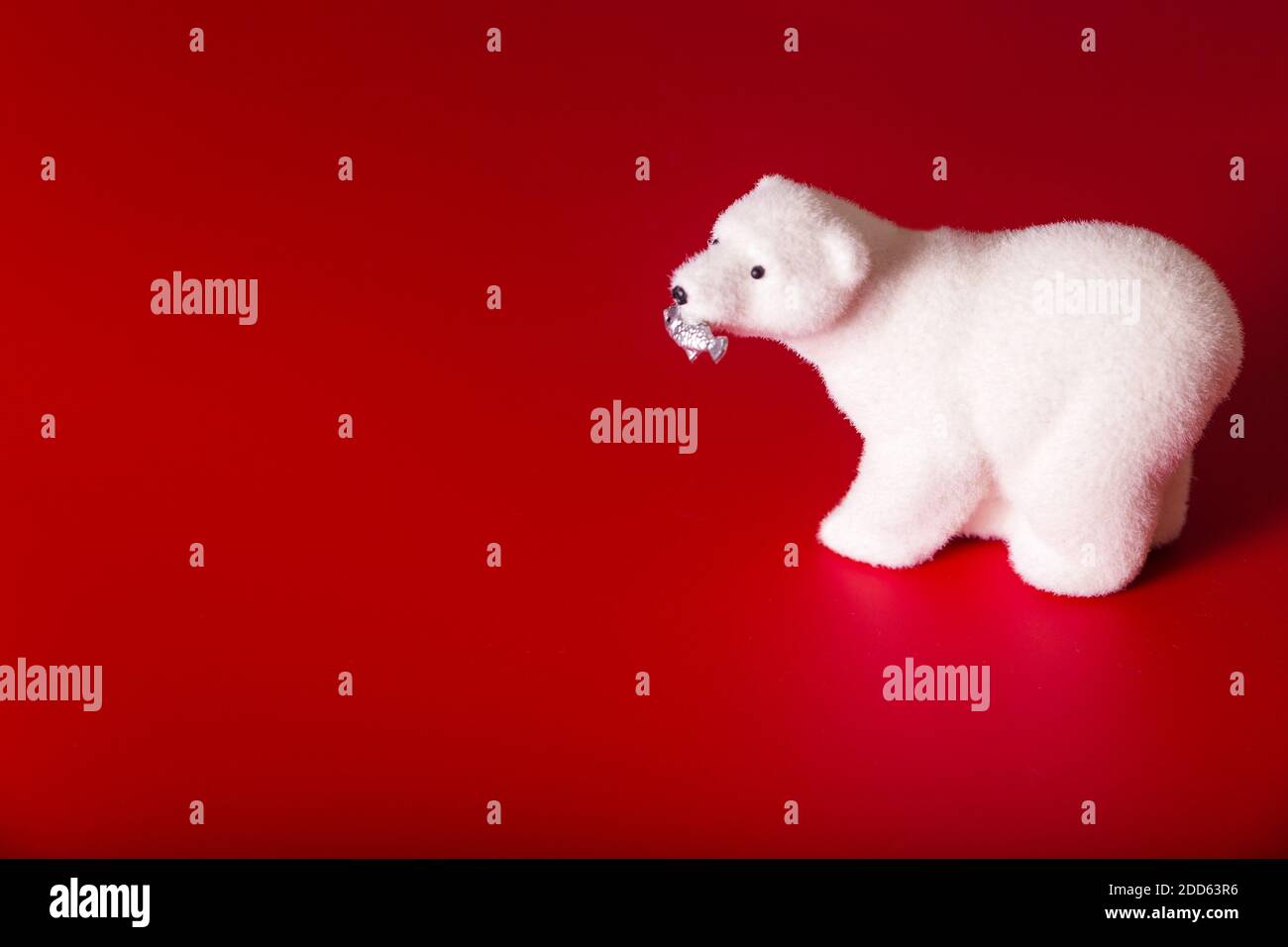 Orso polare giocattolo con pesce in bocca su sfondo rosso Foto Stock