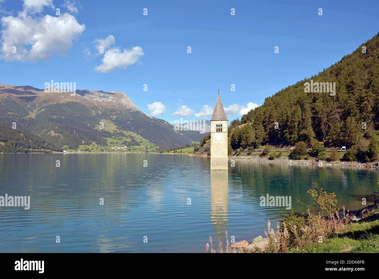 La vecchia torre della chiesa di Graun sul lago Reschen in Val Venosta Foto Stock