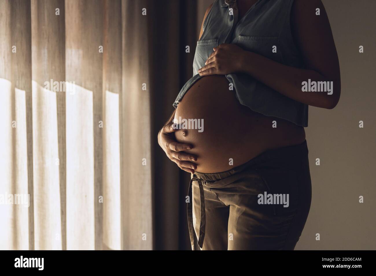 Donna incinta che tocca il ventre al mattino Foto Stock