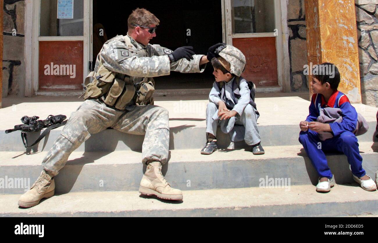 NO FILM, NO VIDEO, NO TV, NO DOCUMENTARIO - SGT. Glen Rice, di Jamestown, Pennsylvania, dalla quarta Brigata della X Divisione montagna, con sede a Fort Polk, Louisiana, intrattiene un ragazzo afghano con il suo casco protettivo vicino al quartier generale della polizia del distretto di Moqor nella provincia di Ghazni, in Afghanistan, all'inizio di settembre 2006. Le forze americane nel sud-est dell'Afghanistan hanno iniziato a fare ciò che molti esperti hanno detto che gli Stati Uniti avrebbero dovuto fare tre anni fa: La costruzione della nazione. Invece di concentrarsi esclusivamente sulla lotta contro i talebani e di rintracciare Osama bin Laden, stanno cercando di ripristinare la gova locale Foto Stock