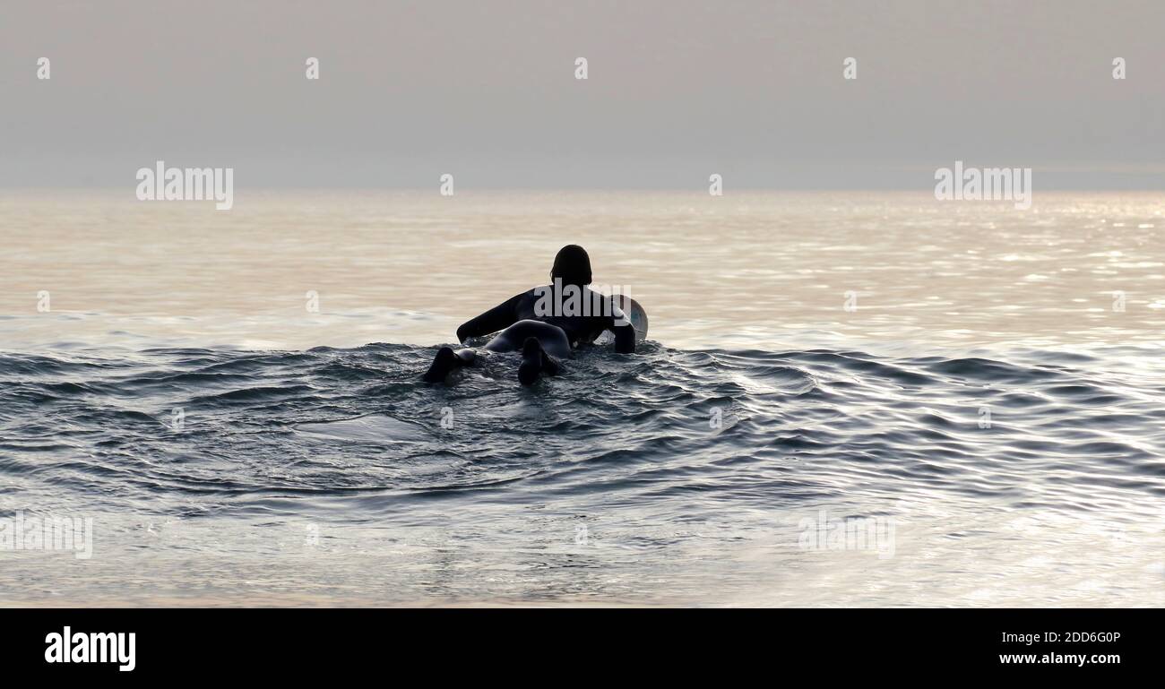 singolo surfer maschio che posa sulla sua tavola in attesa del onda destra Foto Stock