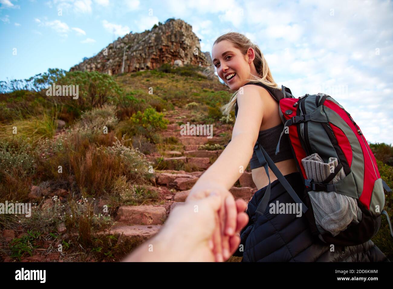 Punto di vista di una giovane donna attiva che camminano lungo percorso in campagna incoraggiando off screen partner a seguirla tenendo la mano Foto Stock