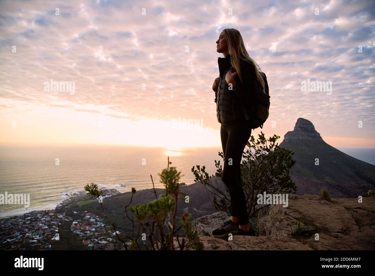 Giovane donna in vacanza camminando lungo il sentiero costiero al tramonto o prendere l'alba sedendosi e guardando il sole tramontare sul mare Foto Stock