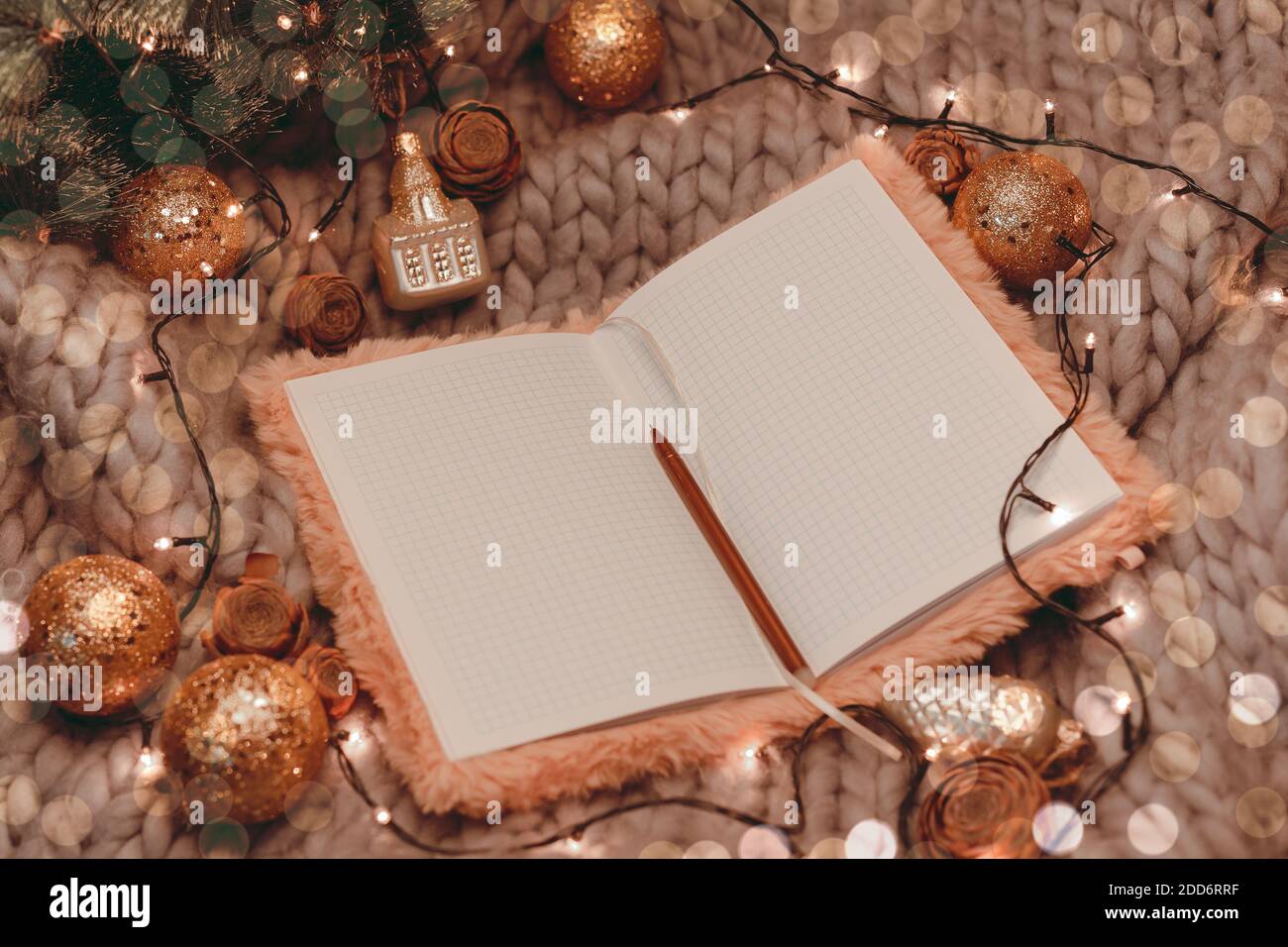 Taccuino aperto champagne su sfondo grigio lavorato a maglia con decorazioni natalizie, piatto Foto Stock