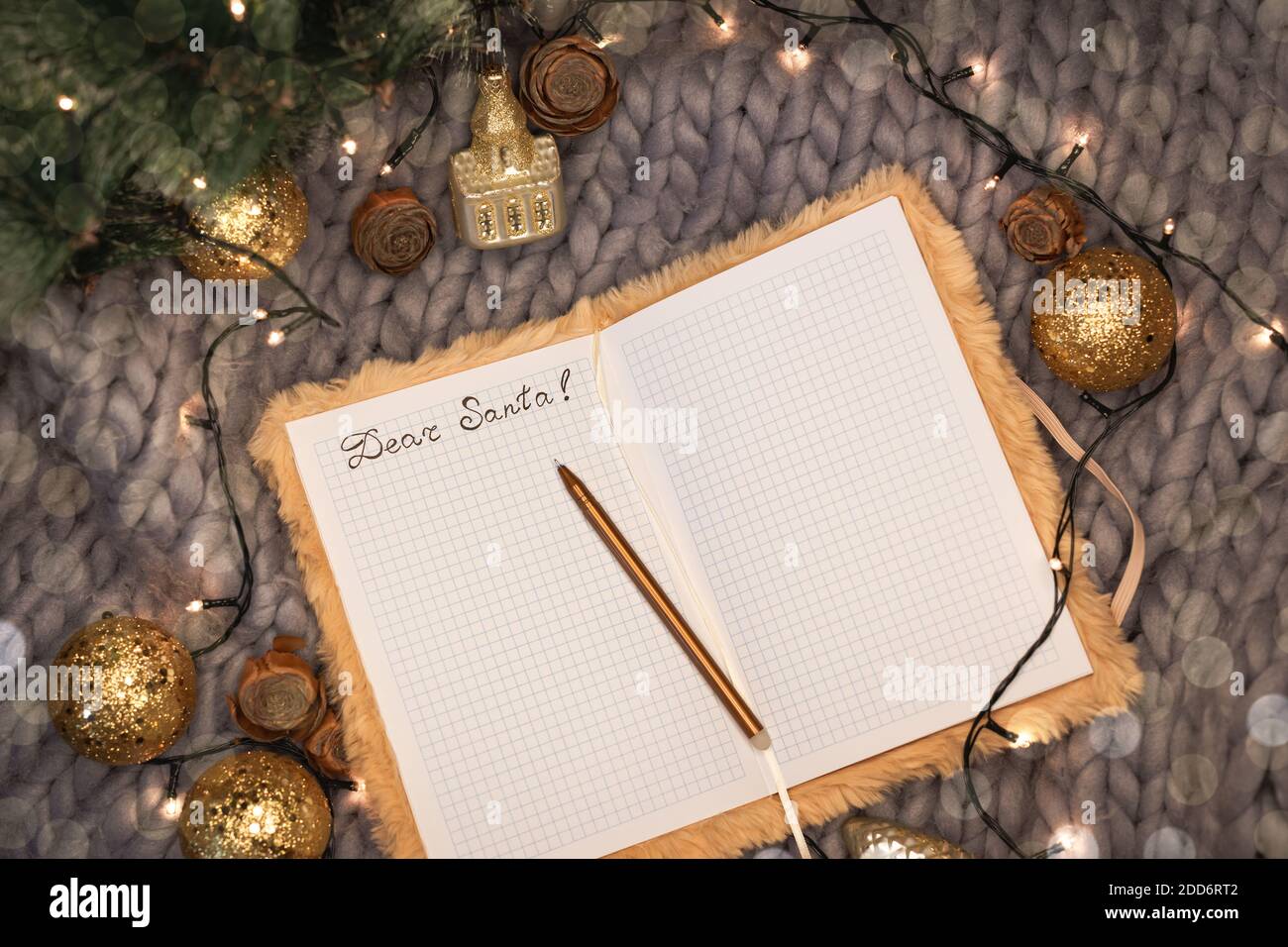 Notepad con l'iscrizione cara santa su sfondo grigio lavorato a maglia con decorazioni natalizie, piatto Foto Stock