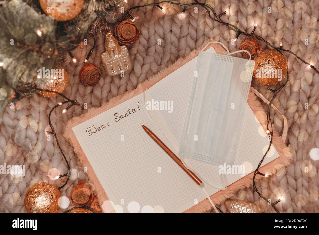 Maschera medica e lettera a santa in blocco note su sfondo lavorato tra le decorazioni natalizie, piatto, set vela Champagne Foto Stock