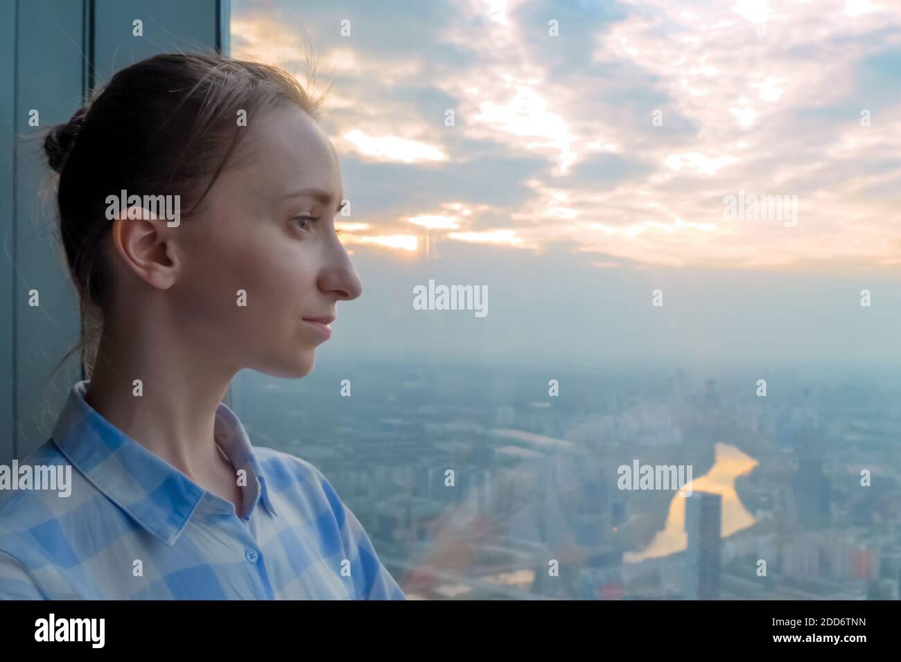 Ritratto di donna pensiva guardando il paesaggio urbano attraverso la finestra di grattacielo Foto Stock