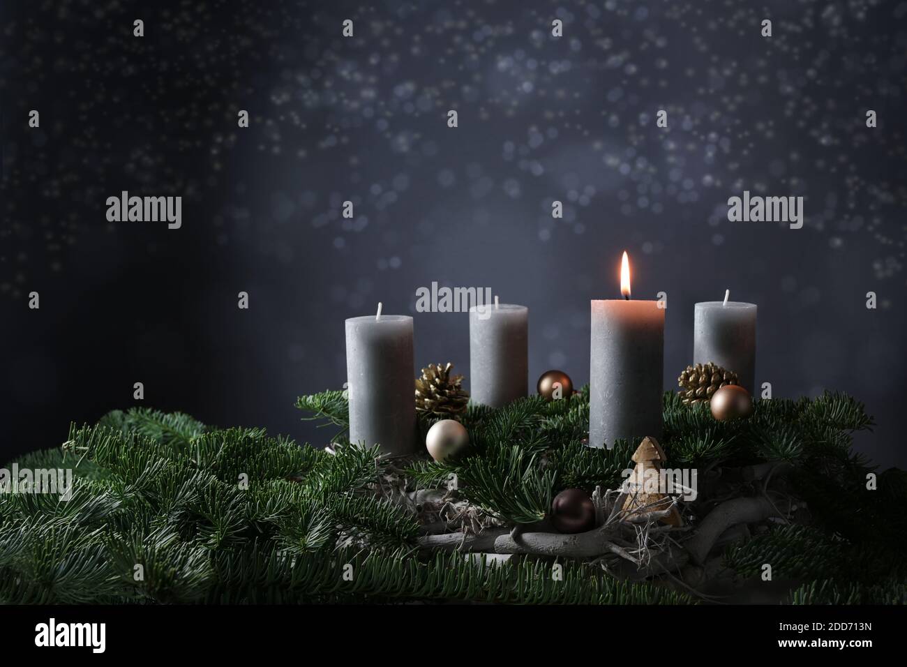 Primo avvento con una candela bruciante su rami di abete con decorazione di Natale contro uno sfondo grigio scuro, spazio di copia, fuoco selezionato, dept stretto Foto Stock