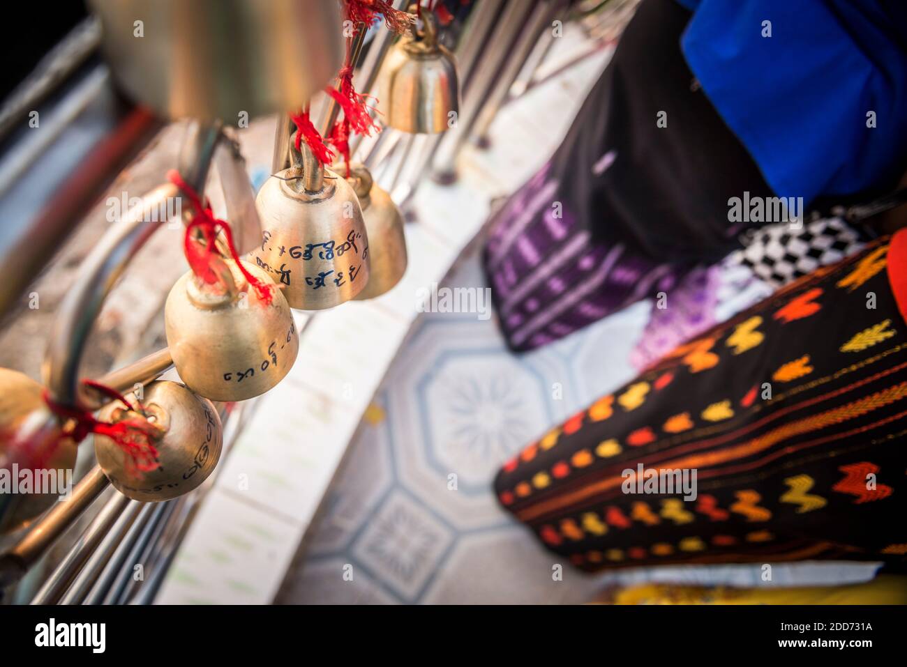 Campane di preghiera e longyi colorati a Golden Rock (Kyaiktiyo Pagoda), Mon state, Myanmar (Birmania) Foto Stock