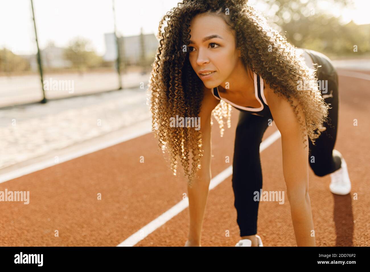 Giovane atletico corridore afroamericano allo stadio di partenza preparandosi per la gara, concetto sportivo Foto Stock