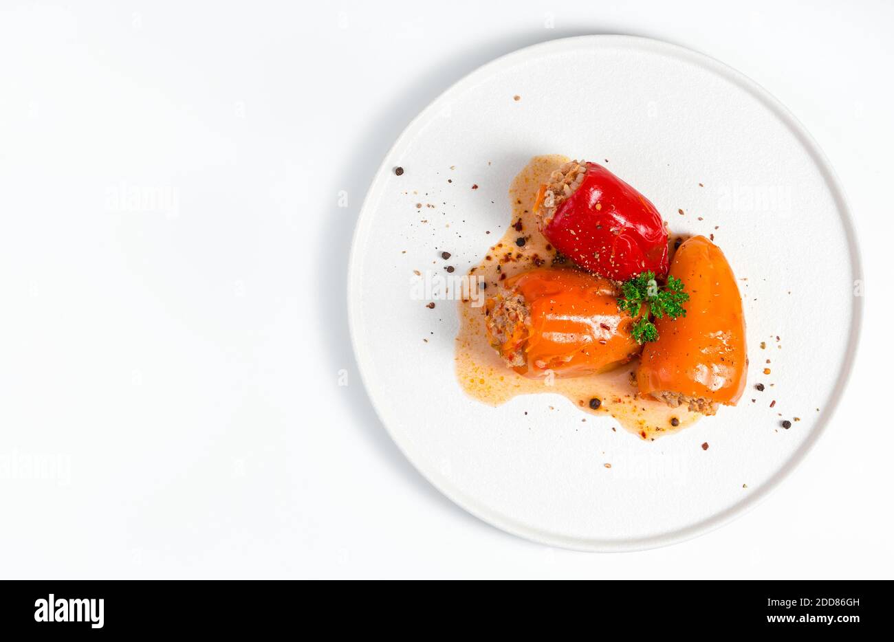 Pepe farcito con prezzemolo verde e spezie su sfondo chiaro in un piatto bianco. Foto Stock