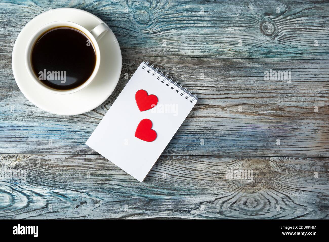 Sfondo romantico con una tazza di caffè e due cuori su un blocco note su  uno sfondo grigio-blu di legno Foto stock - Alamy