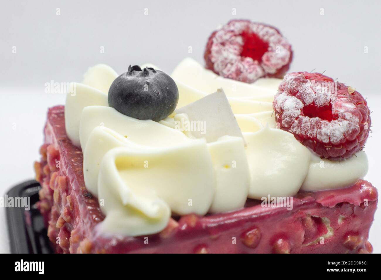 Torta alla crema con panna e lamponi. Un pezzo di torta con frutti di bosco Foto Stock