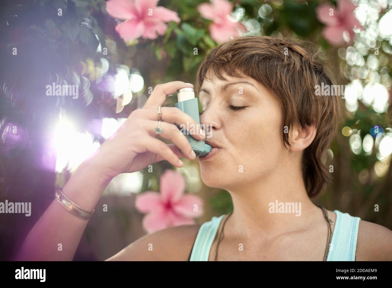 Giovane donna che respira attraverso l'inalatore di asma Foto Stock