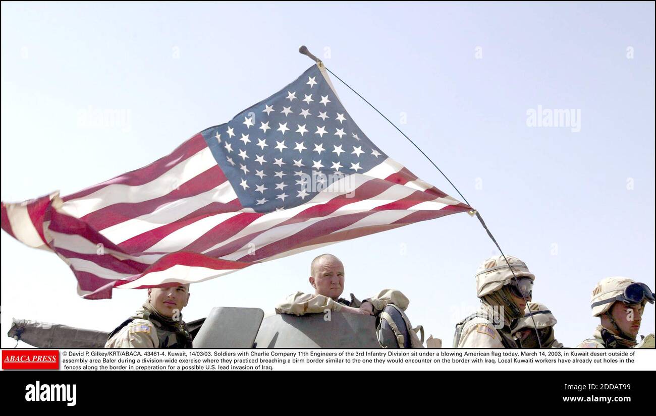 NESSUN FILM, NESSUN VIDEO, NO TV, NESSUN DOCUMENTARIO - © DAVID P. GILKEY/KRT/ABACA. 43461-4. Kuwait, 14/03/03. Soldati con Charlie Company 11th ingegneri della terza Divisione Fanteria sedersi sotto una bandiera americana soffiata oggi, 14 marzo 2003, nel deserto del Kuwait al di fuori dell'area di assemblaggio Baler durante una divisione-wi Foto Stock