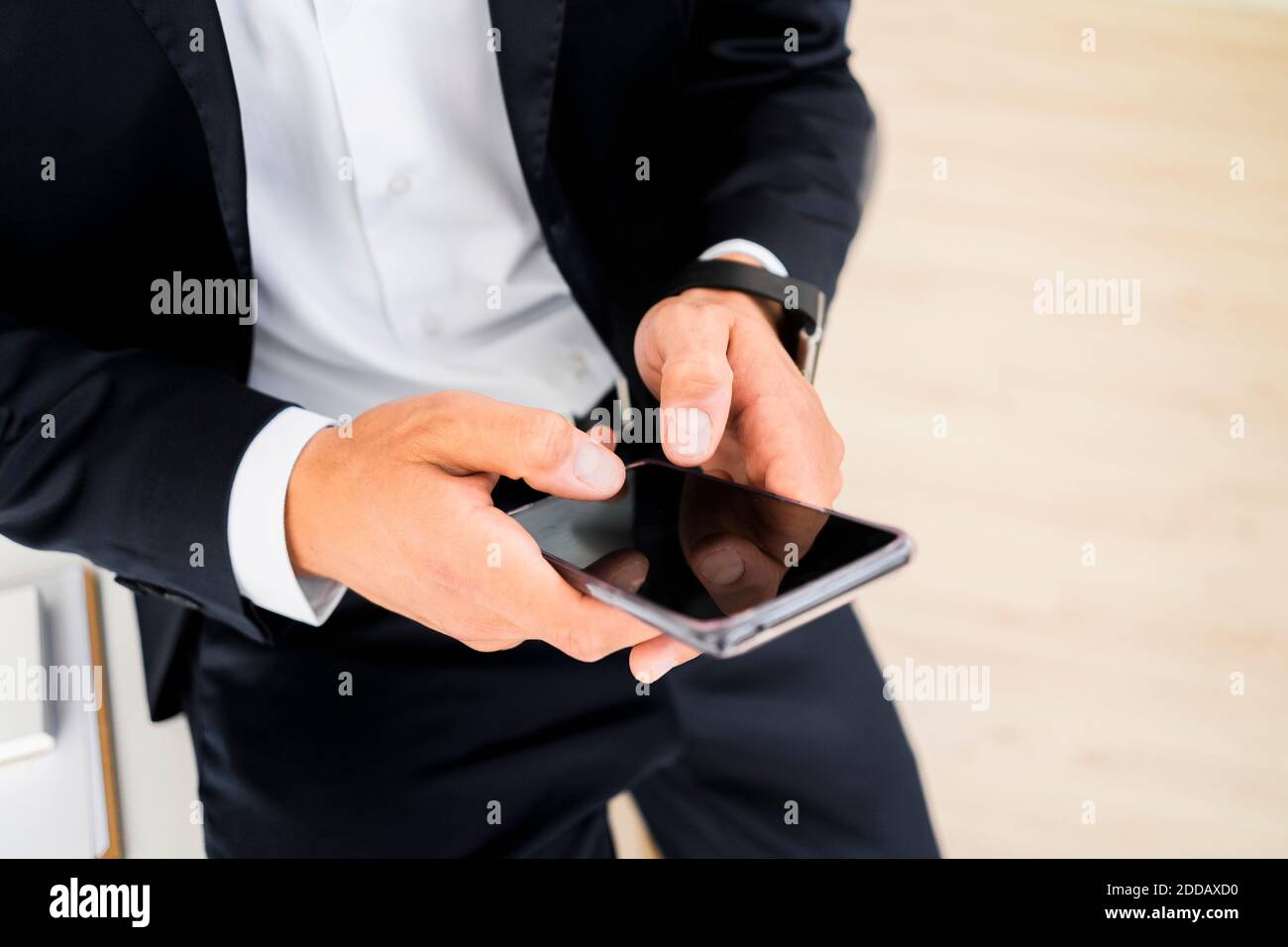 La sezione centrale di giovane imprenditore maschio usando il telefono intelligente alla creatività luogo di lavoro Foto Stock