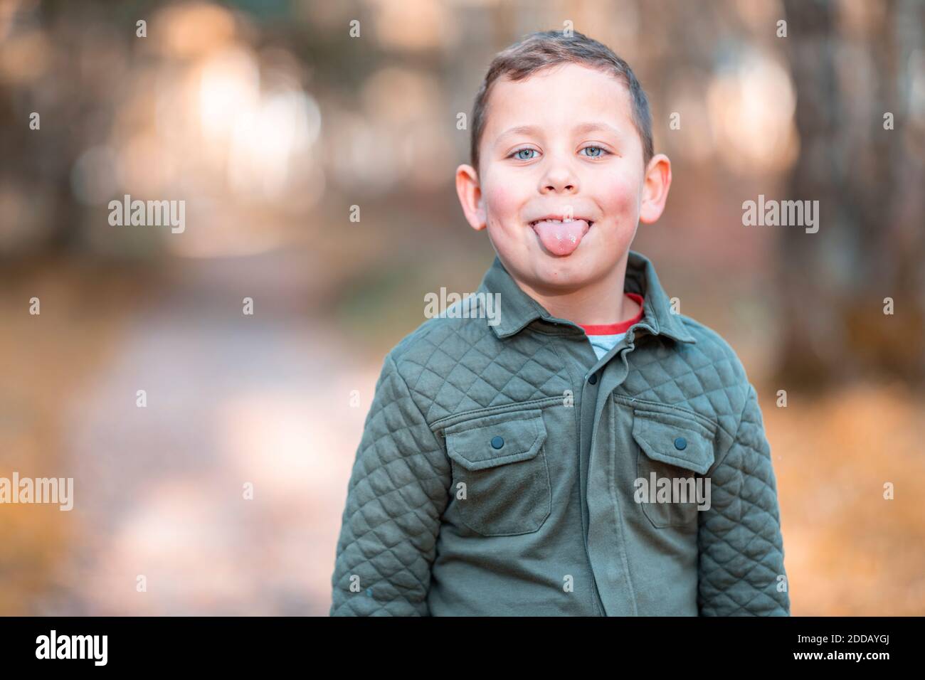 Ragazzo che si stacca la lingua mentre si trova nel parco durante l'autunno Foto Stock