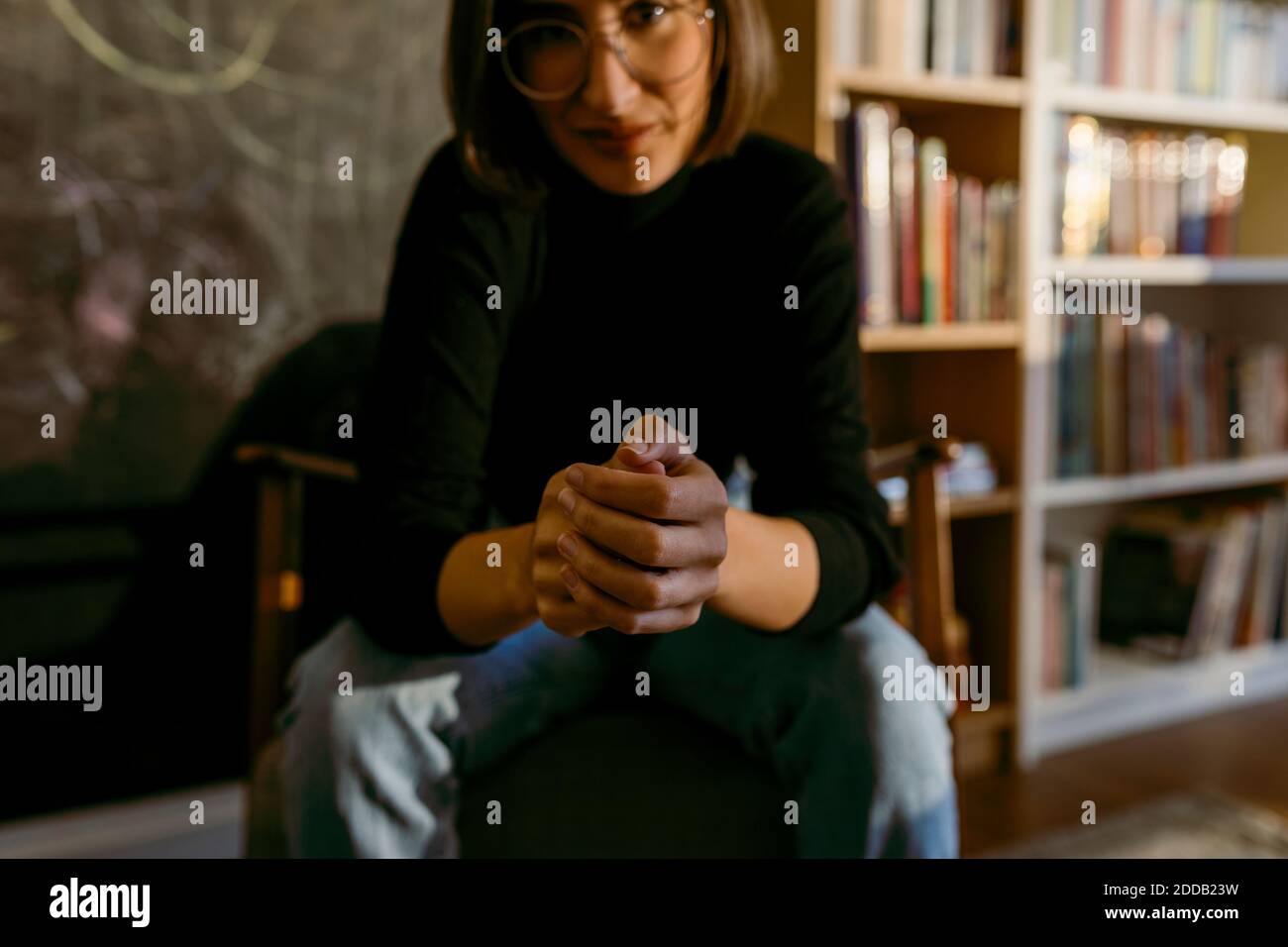 Donna seduta con le mani aggrappate a casa Foto Stock
