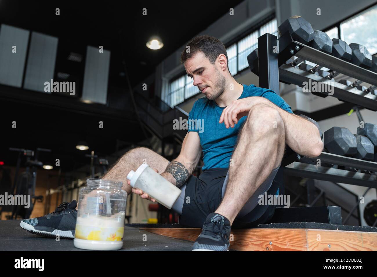 Sportivo che fa tremare le proteine mentre si siede in palestra Foto Stock