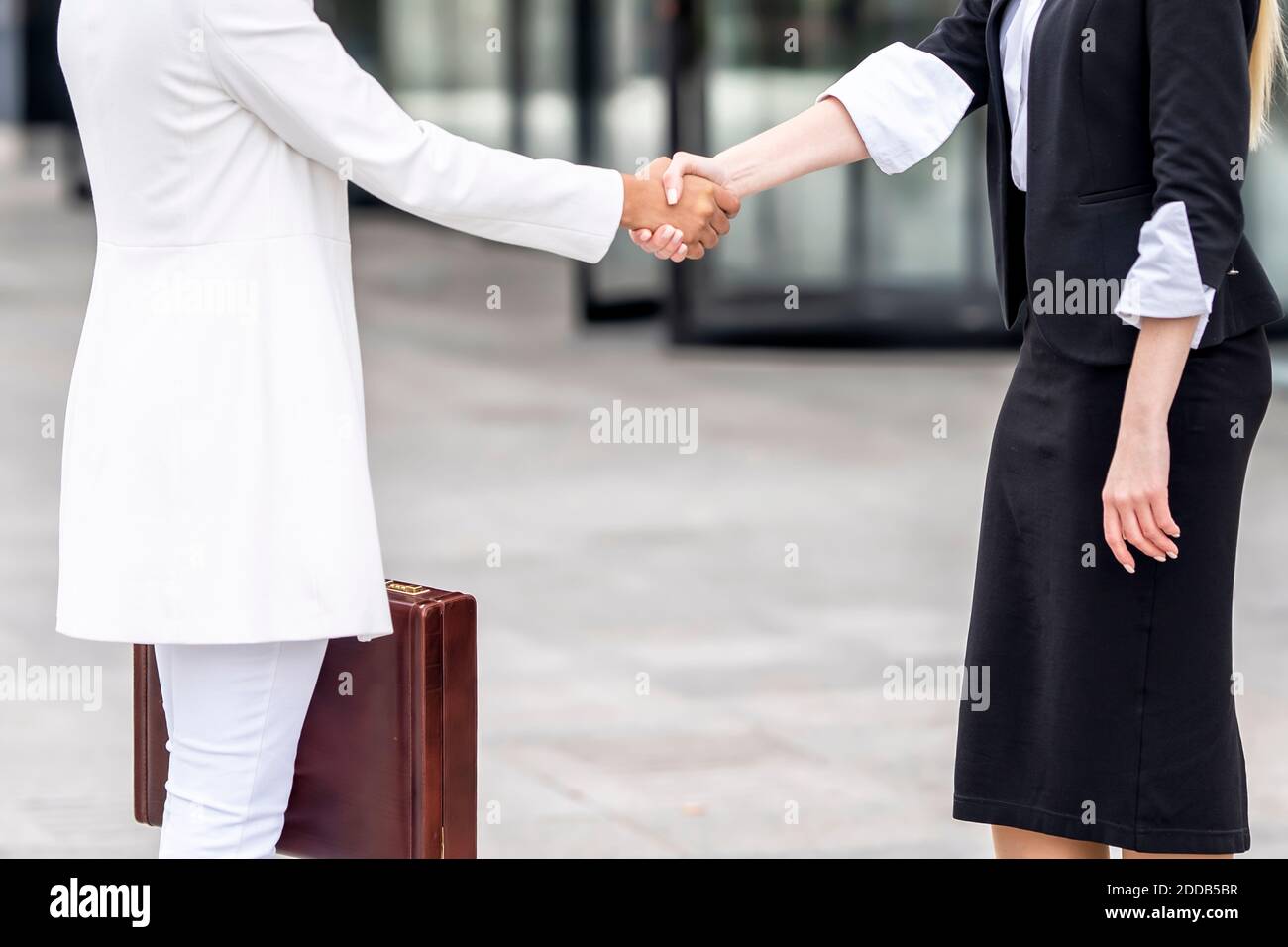 Donne d'affari che fanno stretta di mano mentre si levano in piedi sul sentiero Foto Stock