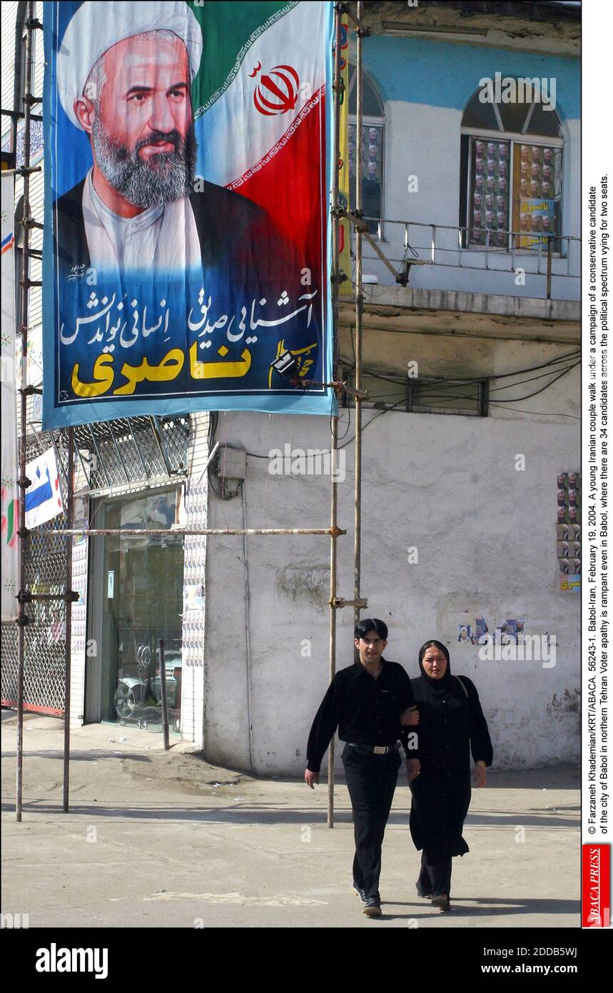 NESSUN FILM, NESSUN VIDEO, NO TV, NESSUN DOCUMENTARIO - © FARZANEH KHADEMIAN/KRT/ABACA. 56243-1. Babol-Iran, 19 febbraio 2004. Una giovane coppia iraniana cammina sotto una campagna di un candidato conservatore della città di Babol nel nord di Teheran Voter apathy è dilagante anche a Babol, dove ci sono 34 candidati in tutto lo spettro politico che si stanno battendo per due seggi. Foto Stock