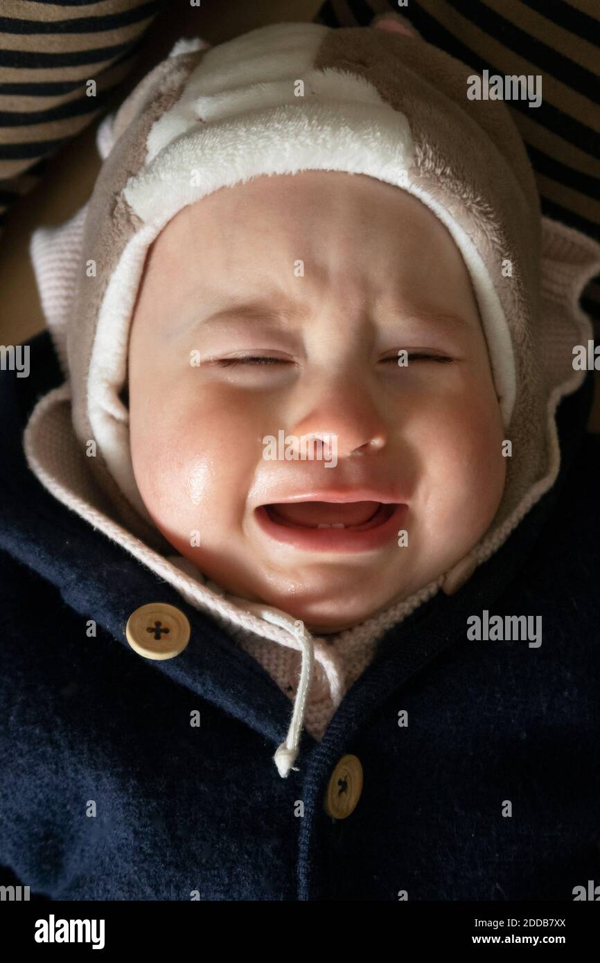 Bambina piangendo mentre si sdraia in casa Foto Stock