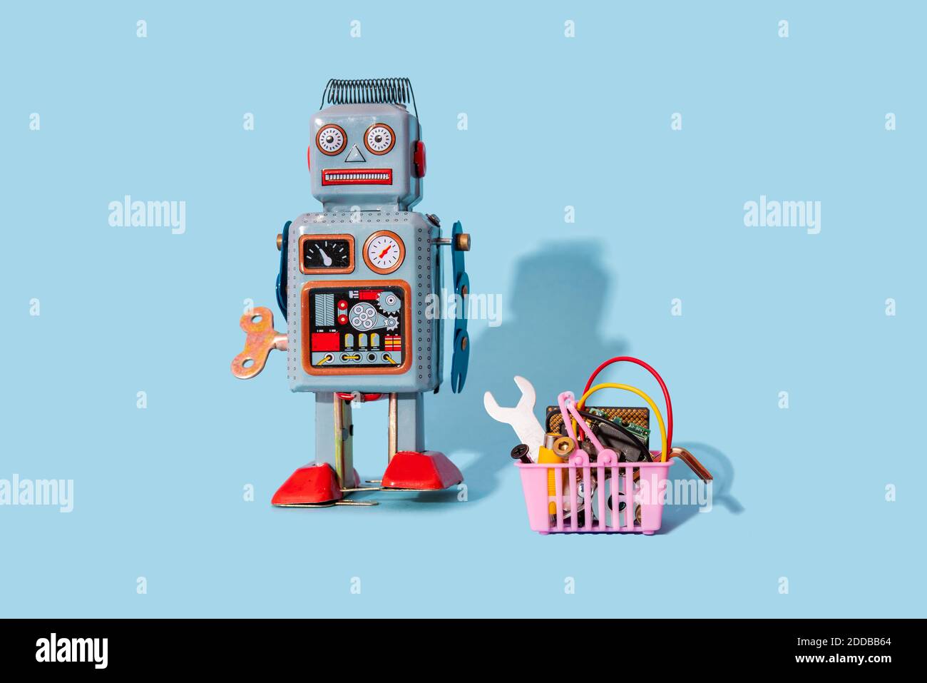 Studio di un giocattolo robot vintage in piedi presso lo shopping in miniatura cestello riempito con apparecchiature elettroniche Foto Stock